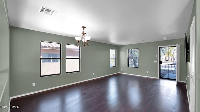 empty room with an inviting chandelier and dark wood-type flooring