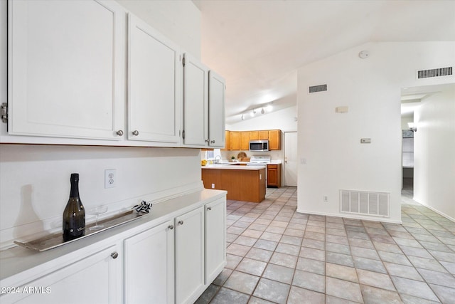 kitchen featuring white cabinets, vaulted ceiling, and light tile patterned flooring