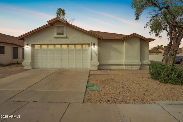 view of front of property with stucco siding, an attached garage, and concrete driveway