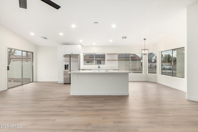 kitchen featuring visible vents, a kitchen island, light countertops, white cabinets, and stainless steel refrigerator with ice dispenser