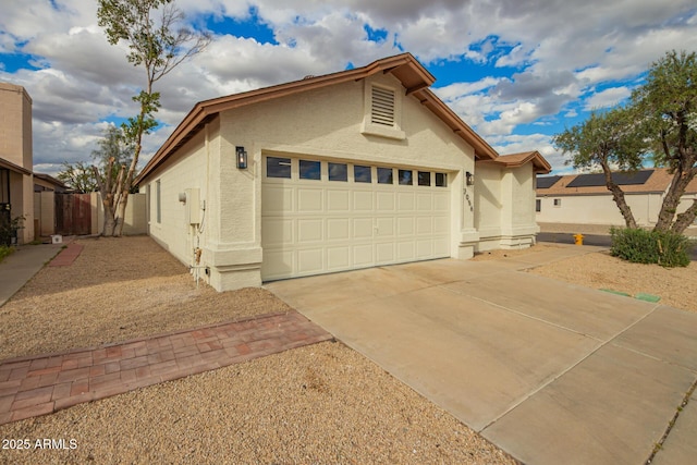 view of property exterior with stucco siding, concrete driveway, an attached garage, and fence