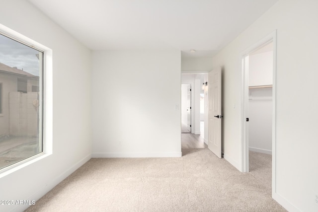 unfurnished bedroom with a spacious closet, carpet flooring, and baseboards