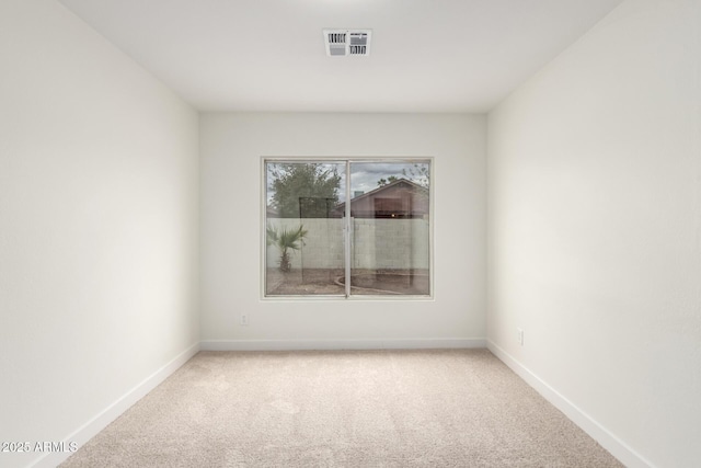 spare room featuring visible vents, light colored carpet, and baseboards