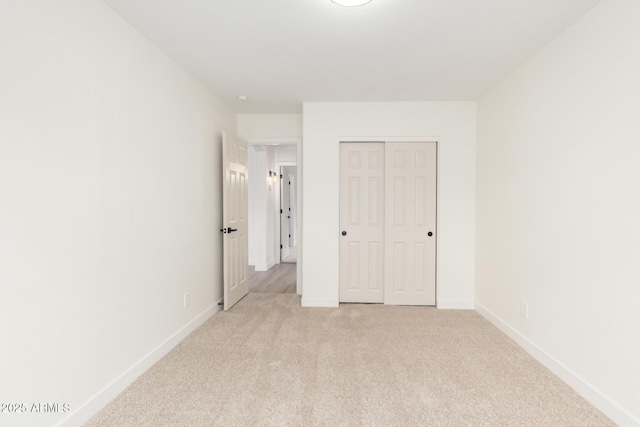 unfurnished bedroom featuring a closet, baseboards, and light carpet