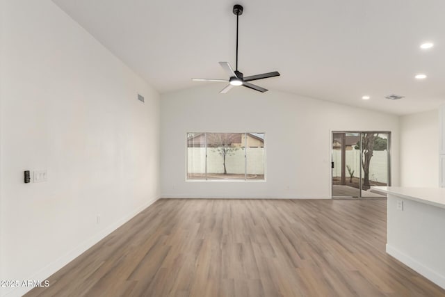 unfurnished living room with baseboards, visible vents, ceiling fan, vaulted ceiling, and light wood-style floors