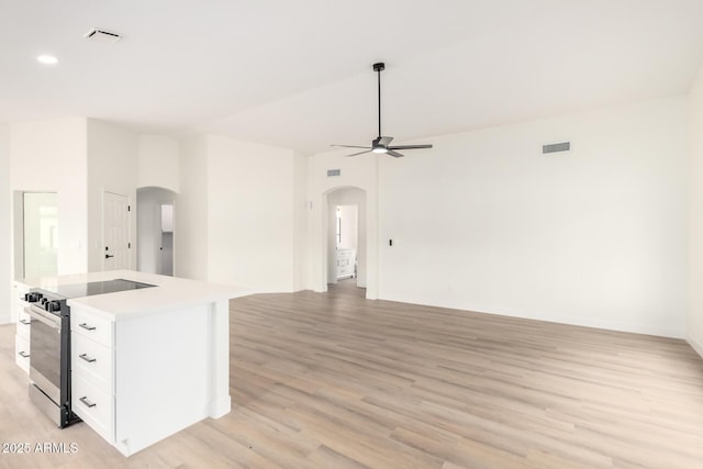 kitchen with arched walkways, open floor plan, stainless steel electric range, and a ceiling fan