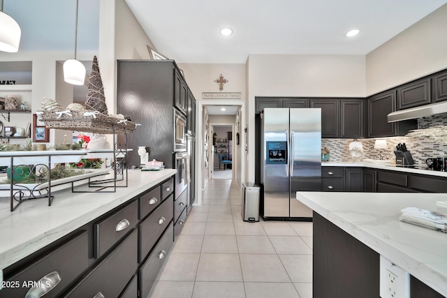 kitchen featuring light stone countertops, decorative light fixtures, decorative backsplash, light tile patterned floors, and appliances with stainless steel finishes