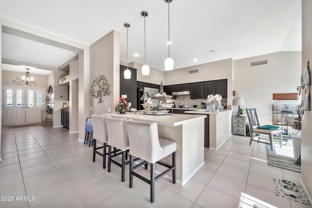 kitchen with kitchen peninsula, light tile patterned floors, decorative light fixtures, and a breakfast bar area