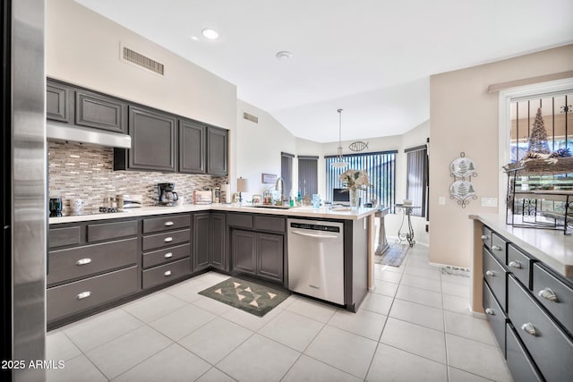 kitchen featuring pendant lighting, vaulted ceiling, tasteful backsplash, kitchen peninsula, and stainless steel appliances