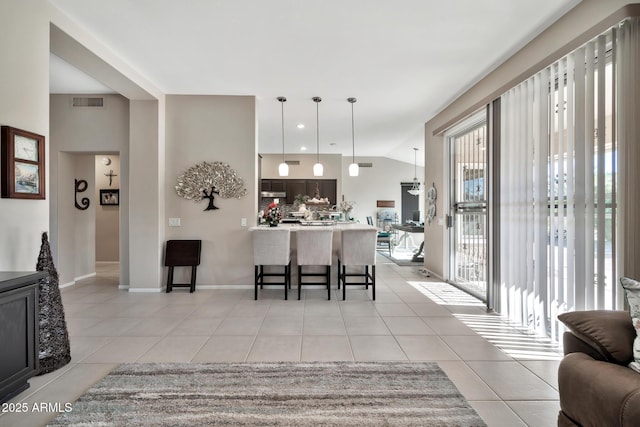 kitchen featuring a kitchen breakfast bar, kitchen peninsula, light tile patterned flooring, and vaulted ceiling