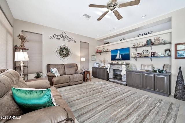 tiled living room featuring ceiling fan and a fireplace