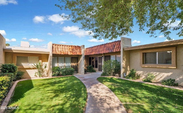 view of front facade with a tiled roof, a front lawn, and stucco siding