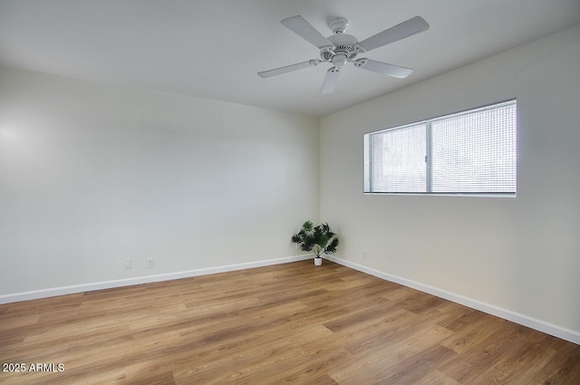 spare room with ceiling fan, light wood-type flooring, and baseboards