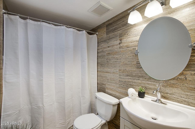 bathroom with visible vents, wood walls, vanity, and toilet