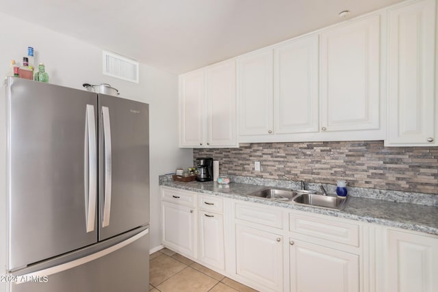 kitchen with light tile patterned floors, sink, stainless steel refrigerator, and white cabinets