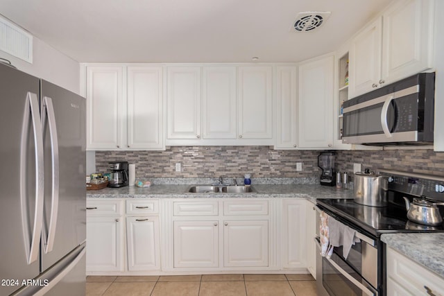 kitchen featuring white cabinetry, stainless steel appliances, light stone counters, and sink