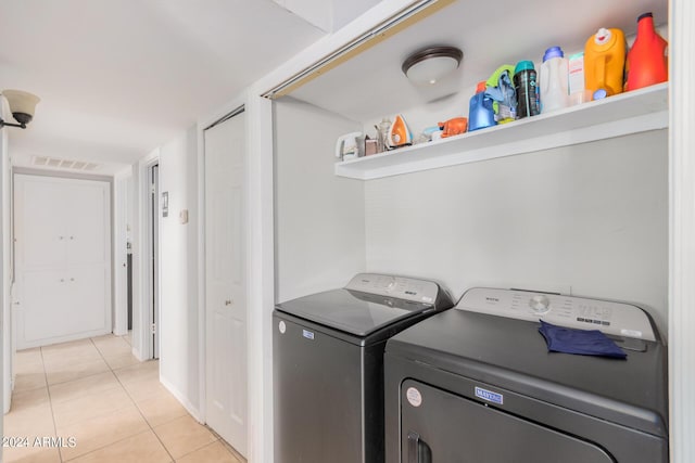 clothes washing area with washer and dryer and light tile patterned floors