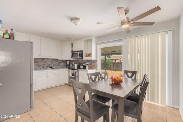 kitchen with appliances with stainless steel finishes, light tile patterned floors, white cabinets, and decorative backsplash