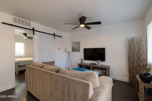 living room featuring ceiling fan, a barn door, and dark hardwood / wood-style floors