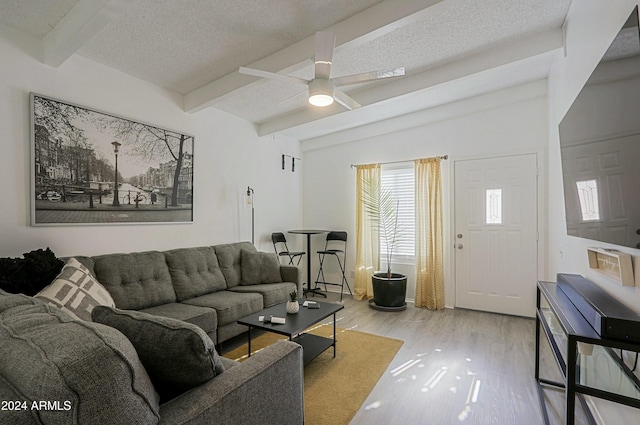 living room with ceiling fan, light hardwood / wood-style flooring, lofted ceiling with beams, and a textured ceiling