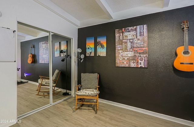 sitting room featuring beamed ceiling and hardwood / wood-style floors