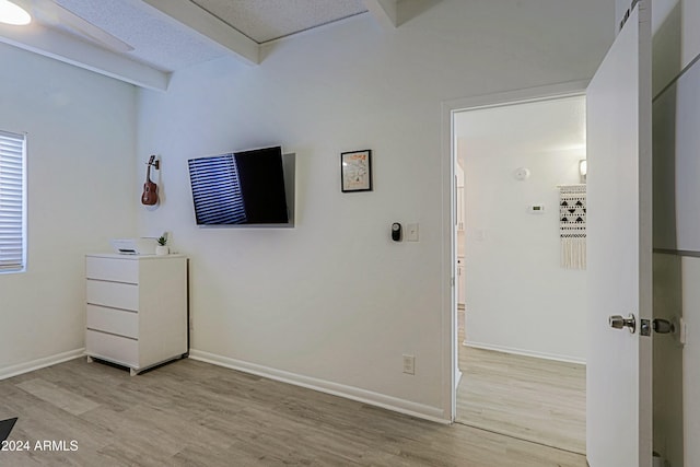 bedroom with light hardwood / wood-style floors and beamed ceiling