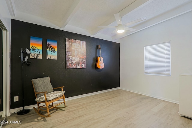 living area featuring ceiling fan, beam ceiling, light hardwood / wood-style flooring, and a textured ceiling