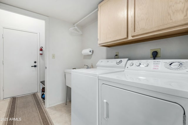 clothes washing area with cabinets and washing machine and dryer