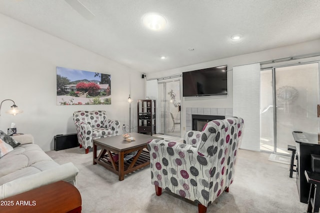 living room with light colored carpet, lofted ceiling, a tile fireplace, and a textured ceiling