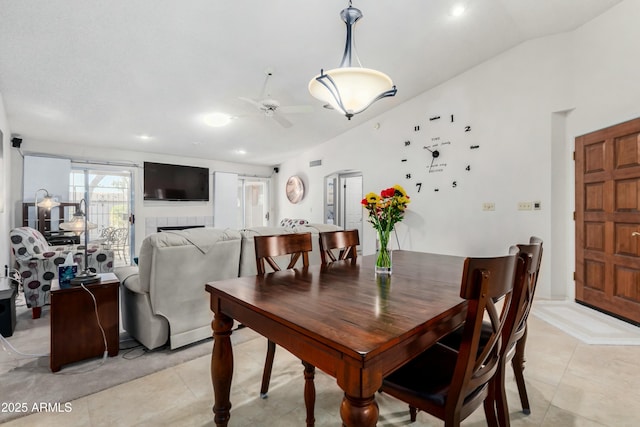 tiled dining room with a tiled fireplace, lofted ceiling, and ceiling fan