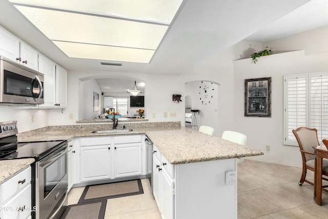 kitchen featuring sink, stainless steel appliances, white cabinets, light tile patterned flooring, and kitchen peninsula