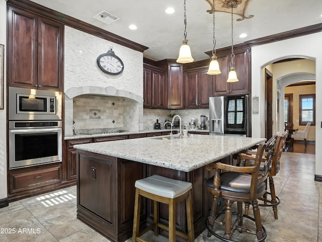 2822 E Constance Way, Phoenix, AZ 85042 - kitchen featuring stainless steel appliances, arched walkways, crown molding, backsplash, and a breakfast bar