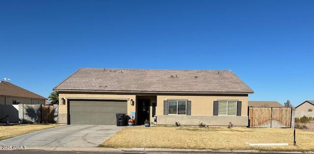 single story home featuring driveway, an attached garage, fence, and stucco siding