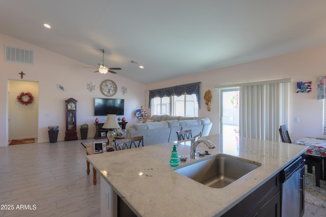 kitchen featuring light stone counters, a center island with sink, visible vents, open floor plan, and a sink