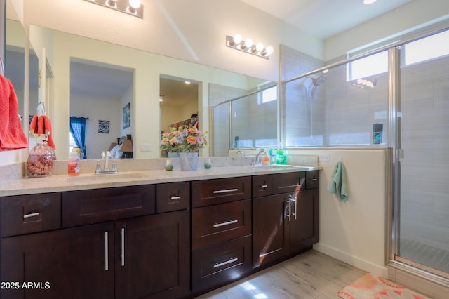 bathroom featuring wood finished floors, a sink, a shower stall, and double vanity