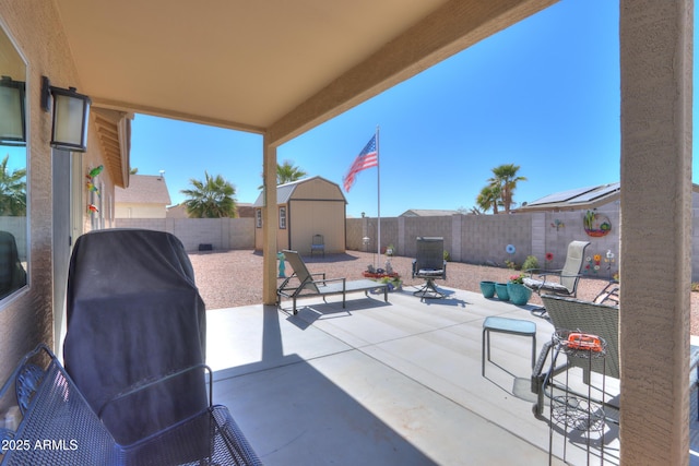 view of patio with a fenced backyard, an outdoor structure, and a storage unit