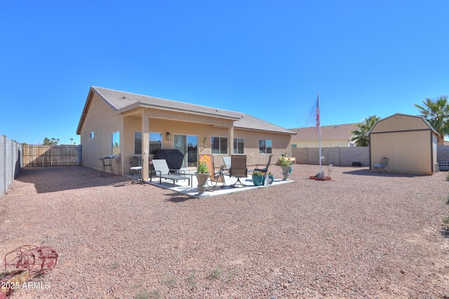 rear view of property with a patio area, a fenced backyard, a storage unit, and stucco siding