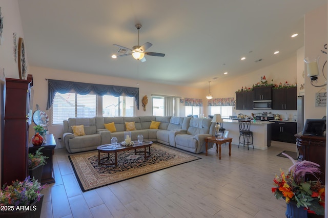 living room with high vaulted ceiling, plenty of natural light, light wood finished floors, and ceiling fan