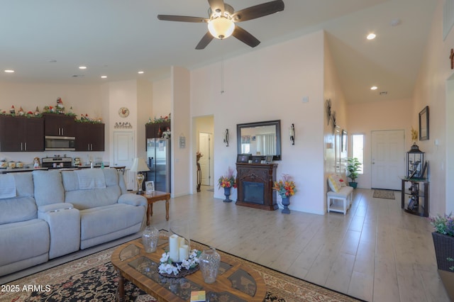 living area with high vaulted ceiling, a ceiling fan, light wood-style flooring, and recessed lighting