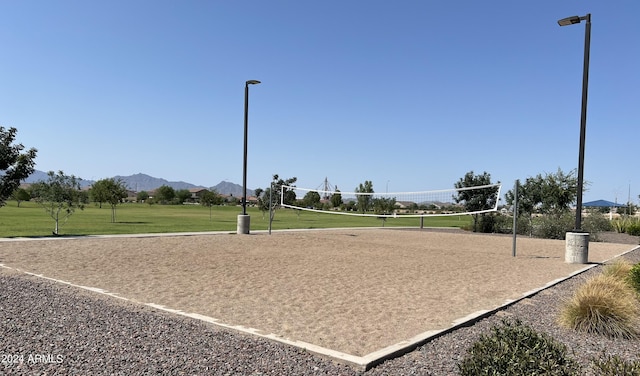 view of property's community with volleyball court, a mountain view, and a lawn