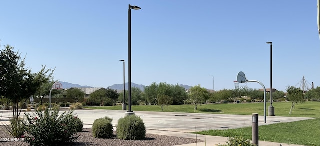 view of community featuring a lawn, a mountain view, and basketball hoop