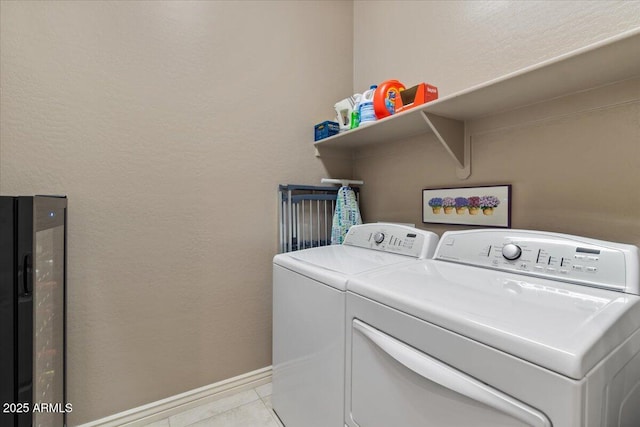 laundry room featuring light tile patterned floors, laundry area, washer and clothes dryer, and baseboards