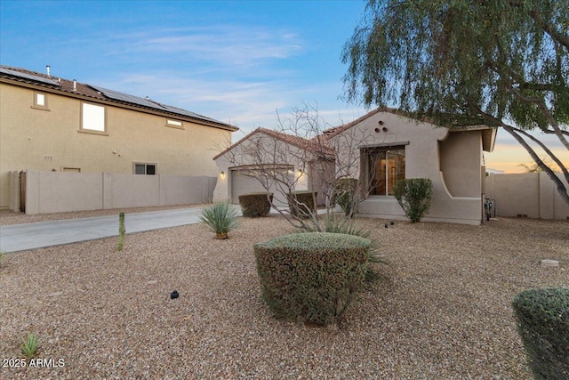 back of house with a garage, concrete driveway, fence, and stucco siding