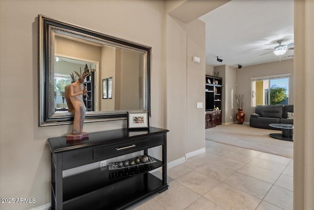 corridor featuring light colored carpet, light tile patterned flooring, and baseboards