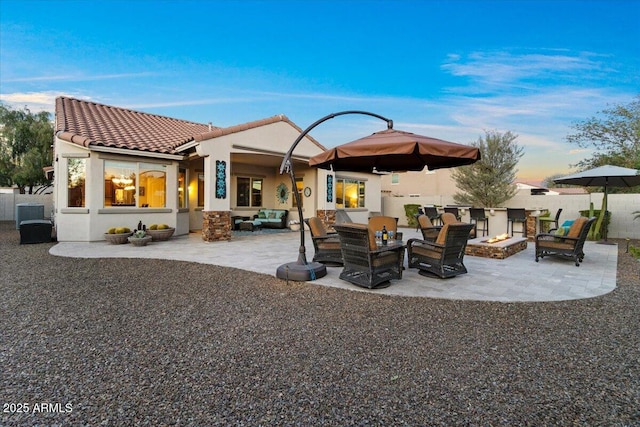 rear view of house with a patio, an outdoor living space with a fire pit, a tiled roof, fence, and stucco siding