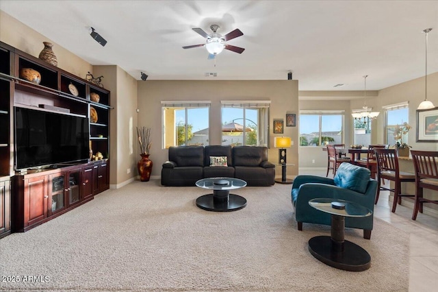 living area featuring visible vents, baseboards, and ceiling fan with notable chandelier