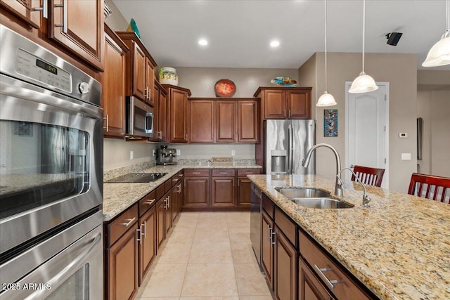 kitchen with appliances with stainless steel finishes, a sink, light stone counters, and pendant lighting