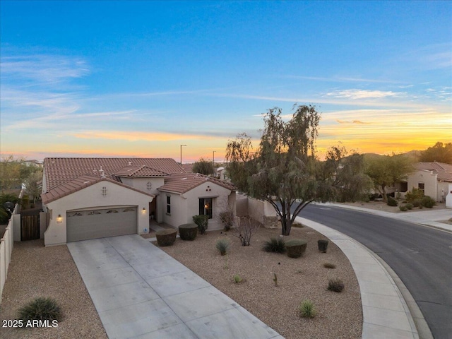 mediterranean / spanish-style house with stucco siding, concrete driveway, an attached garage, fence, and a tiled roof