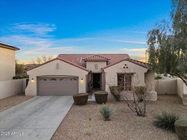 mediterranean / spanish home with a garage, fence, concrete driveway, a tiled roof, and stucco siding