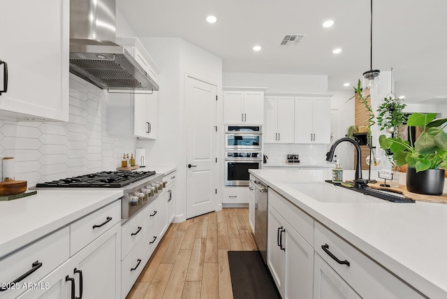 kitchen with extractor fan, a sink, stainless steel appliances, backsplash, and light countertops
